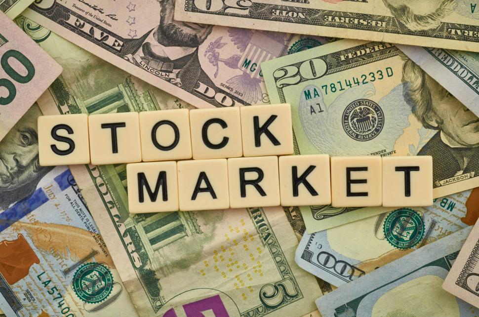 Free Image of Tiles spelling  STOCK MARKET  laid over various currencies 