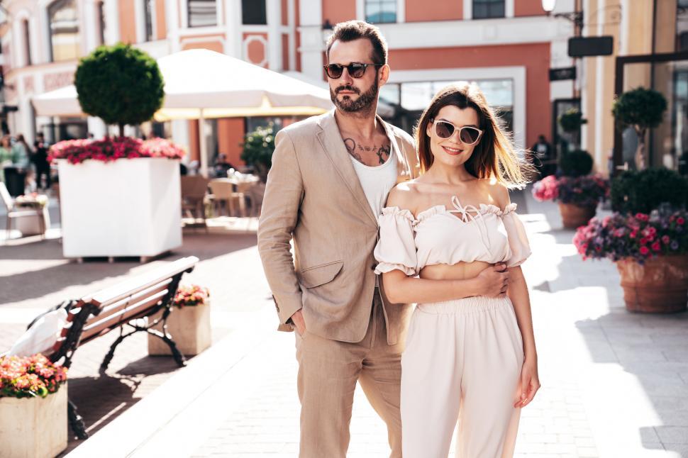 Free Image of Couple enjoying a sunny afternoon in a historic plaza with bustling cafes 