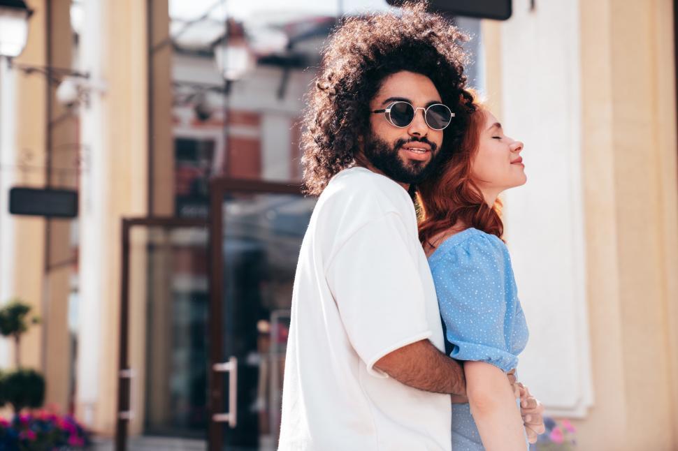 Free Image of Couple enjoying a sunny day together in a vibrant city center while embracing each other warmly 