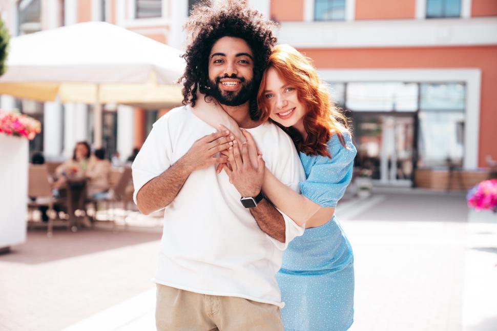 Free Image of Couple enjoying a sunny day in a vibrant outdoor setting while embracing each other and smiling 