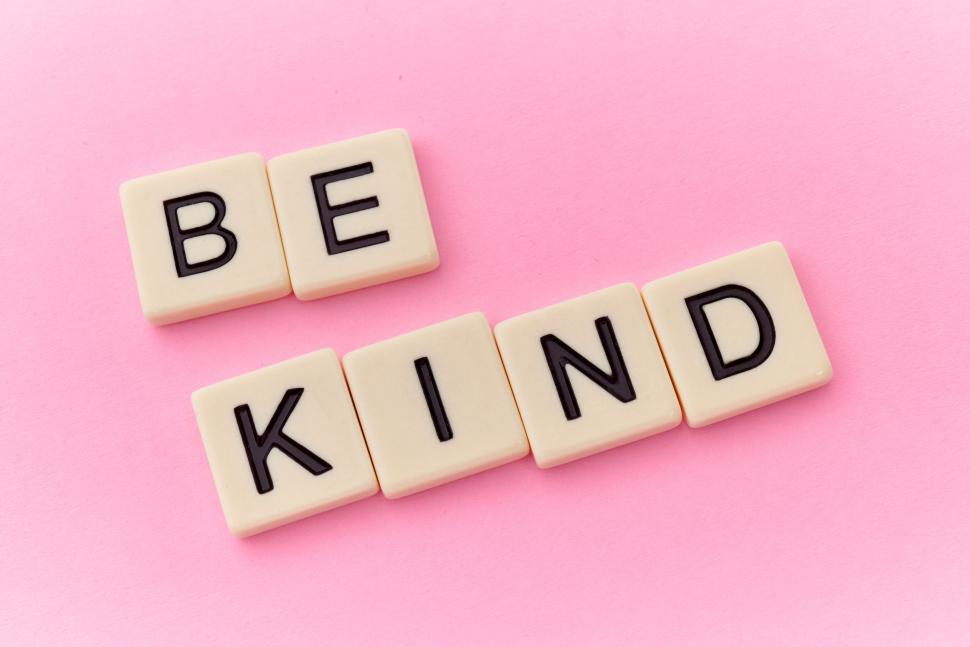 Free Image of The words be kind spelled out with letter tiles on pink 