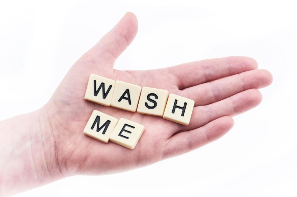 Free Image of Hand holding Scrabble tiles with the words Wash Me visible. 
