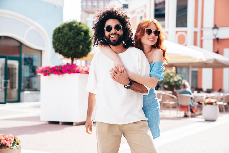 Free Image of Couple enjoying a sunny day in a vibrant outdoor setting with colorful flowers and casual summer attire 