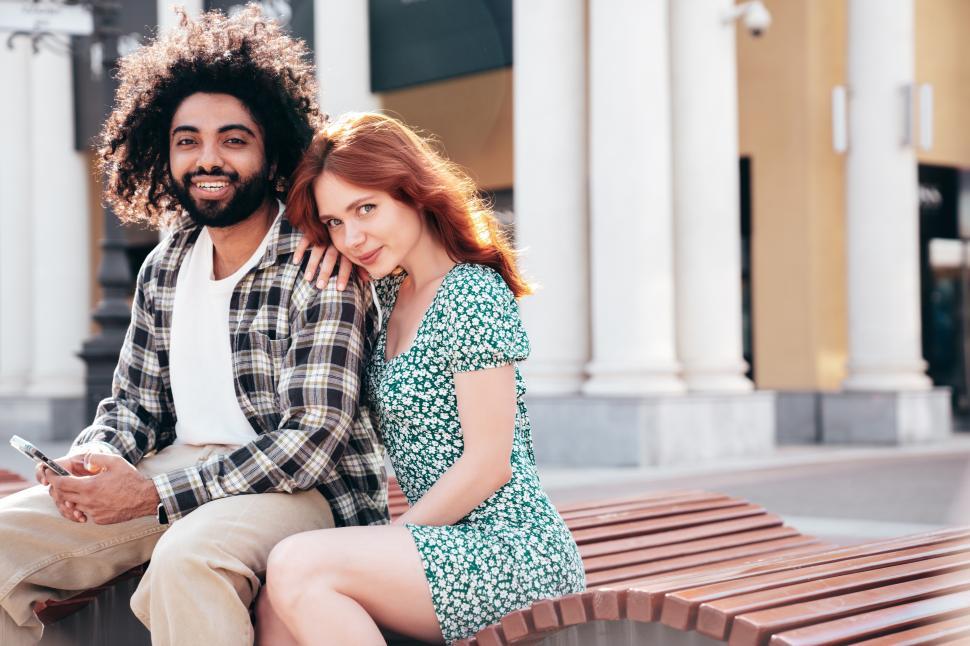 Free Image of Couple enjoying a sunny day in a city park while sitting on a bench and taking a break 