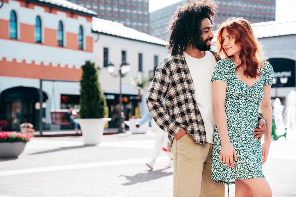 Free Image of Couple enjoying a sunny day in a vibrant urban setting while dressed in stylish outfits with a relaxed atmosphere 