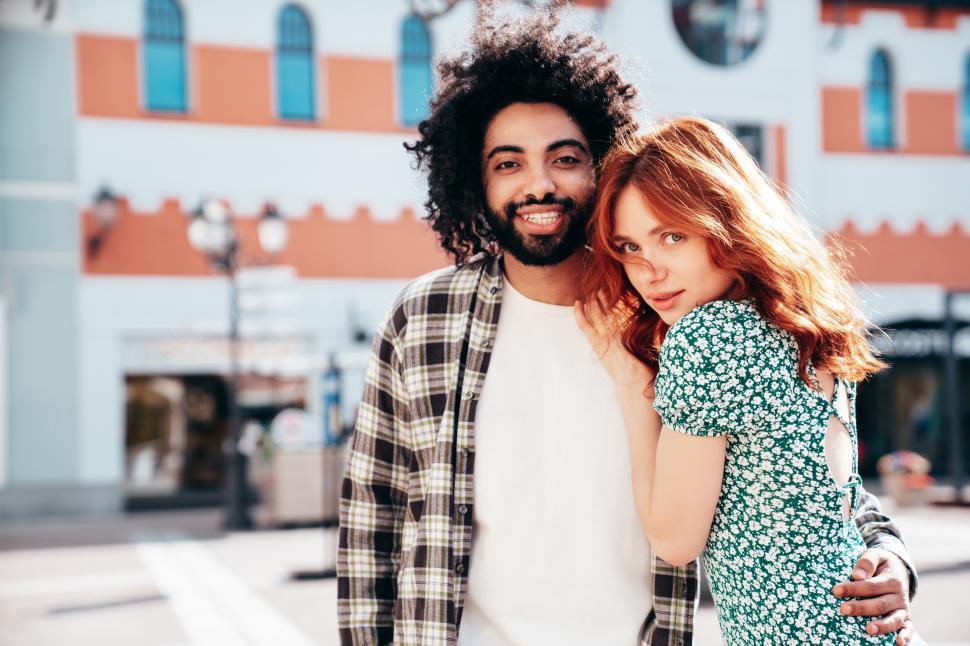 Free Image of Couple enjoys a sunny day together in a vibrant city with colorful architecture and a relaxed atmosphere 