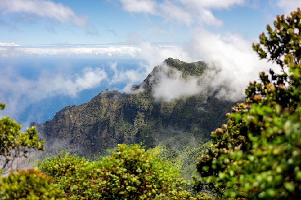 Free Image of Cloud-covered mountain peak with lush green landscape 