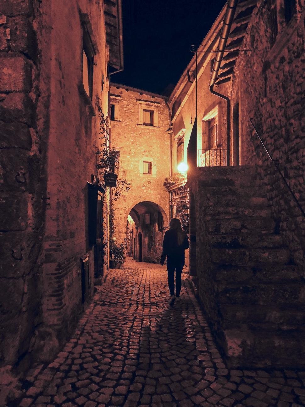 Free Image of Cobbled street at night with a silhouetted lone walker 