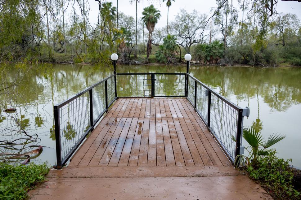 Free Image of Empty wooden dock extending into a calm, reflective lake 