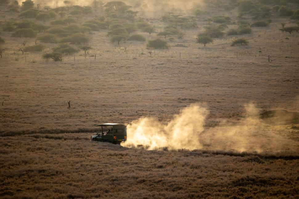 Free Image of Safari vehicle driving through dusty savannah landscape 