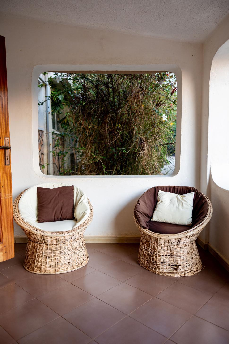 Free Image of Two wicker chairs on a porch with a green view. 