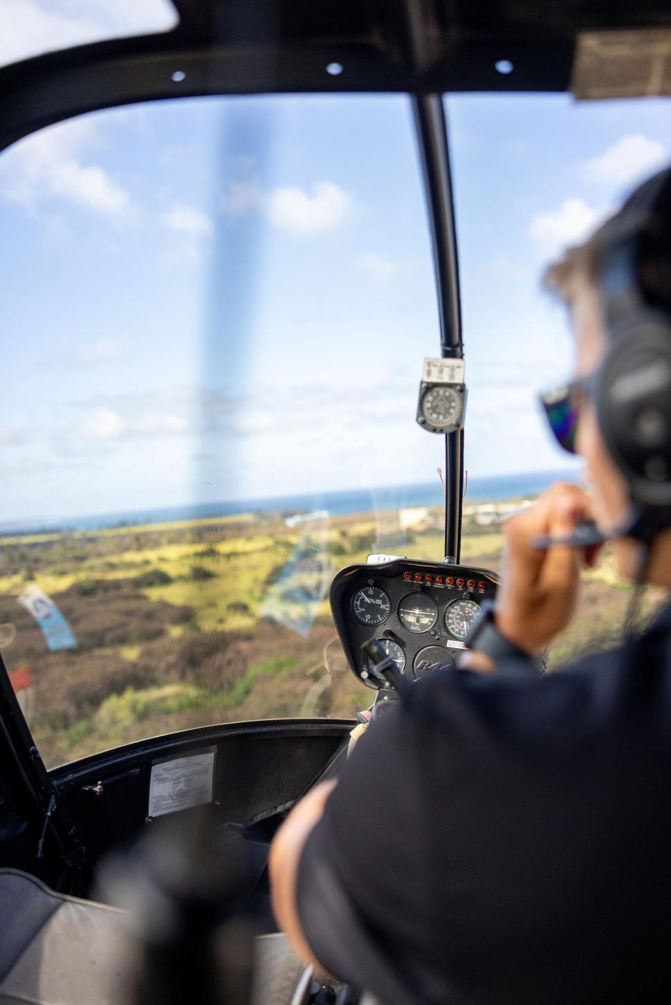 Free Image of Pilot inside helicopter cockpit flying over landscape. 