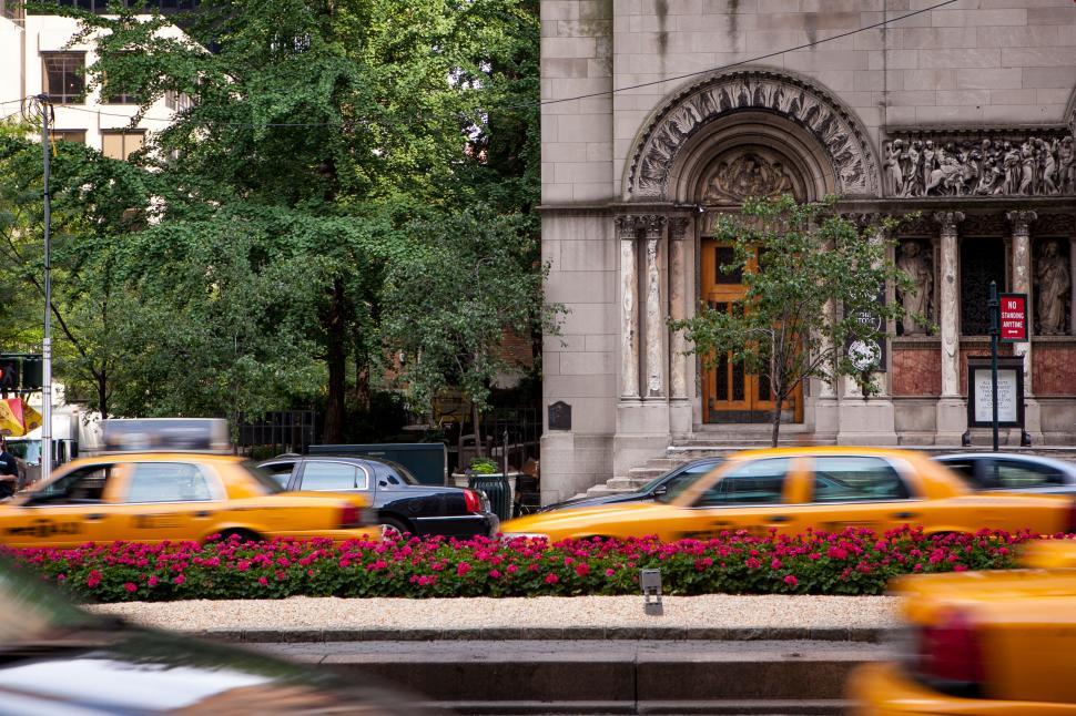 Free Image of Urban scene with yellow taxis and historical building 
