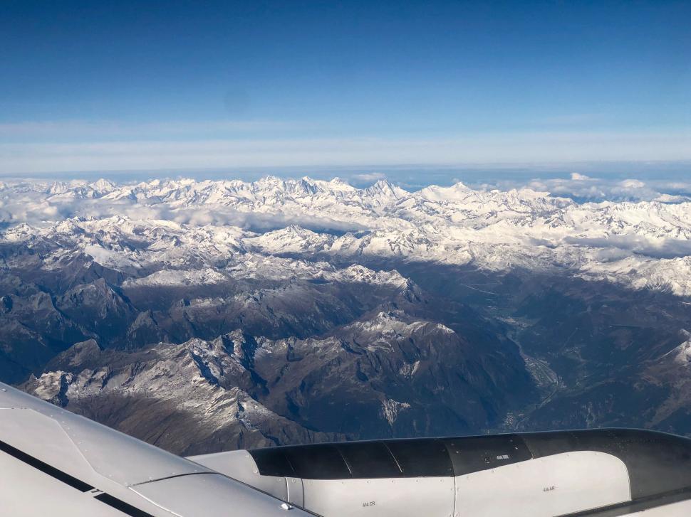 Free Image of Snow-covered mountain range viewed from airplane window 