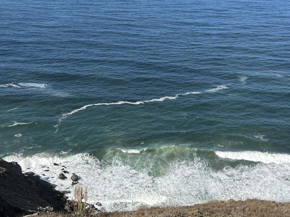 Free Image of Ocean waves hit rocky shoreline on a sunny clear day 