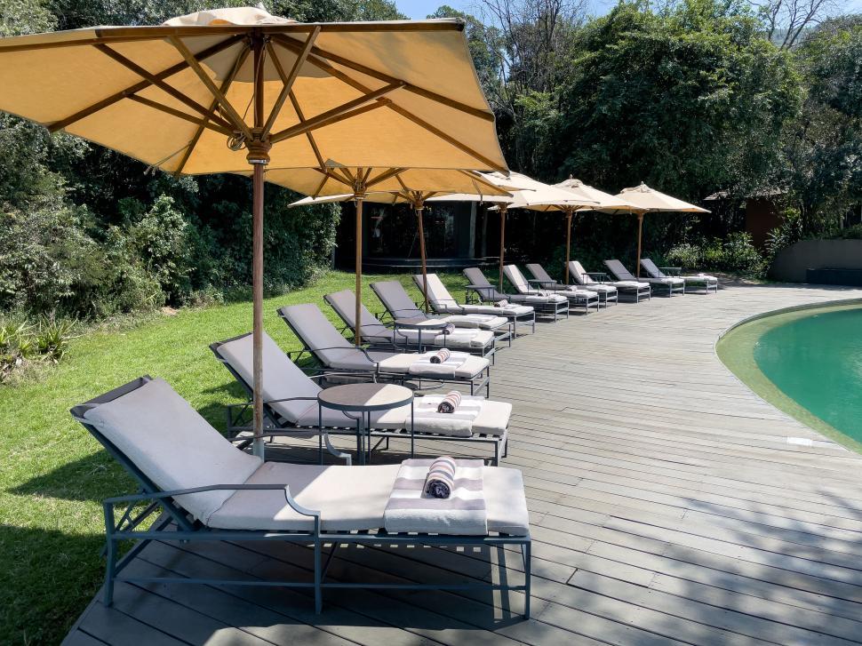 Free Image of Empty poolside loungers under umbrellas on sunny day. 