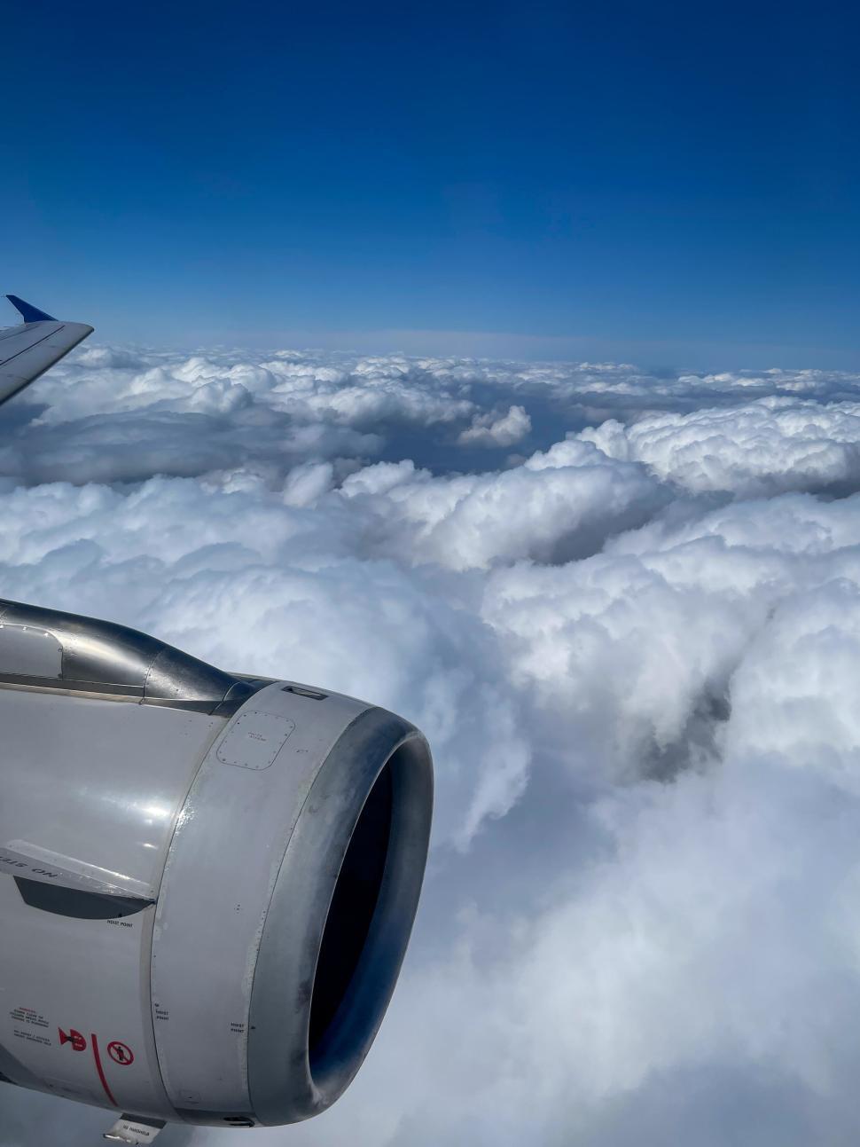 Free Image of Airplane soaring above the clouds, blue sky beyond 