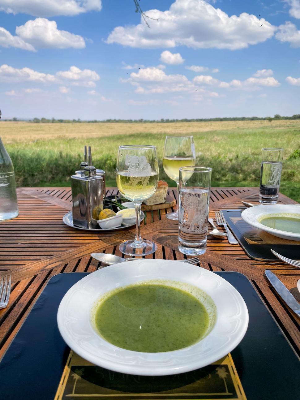 Free Image of Outdoor dining setup with bowls of green soup served. 
