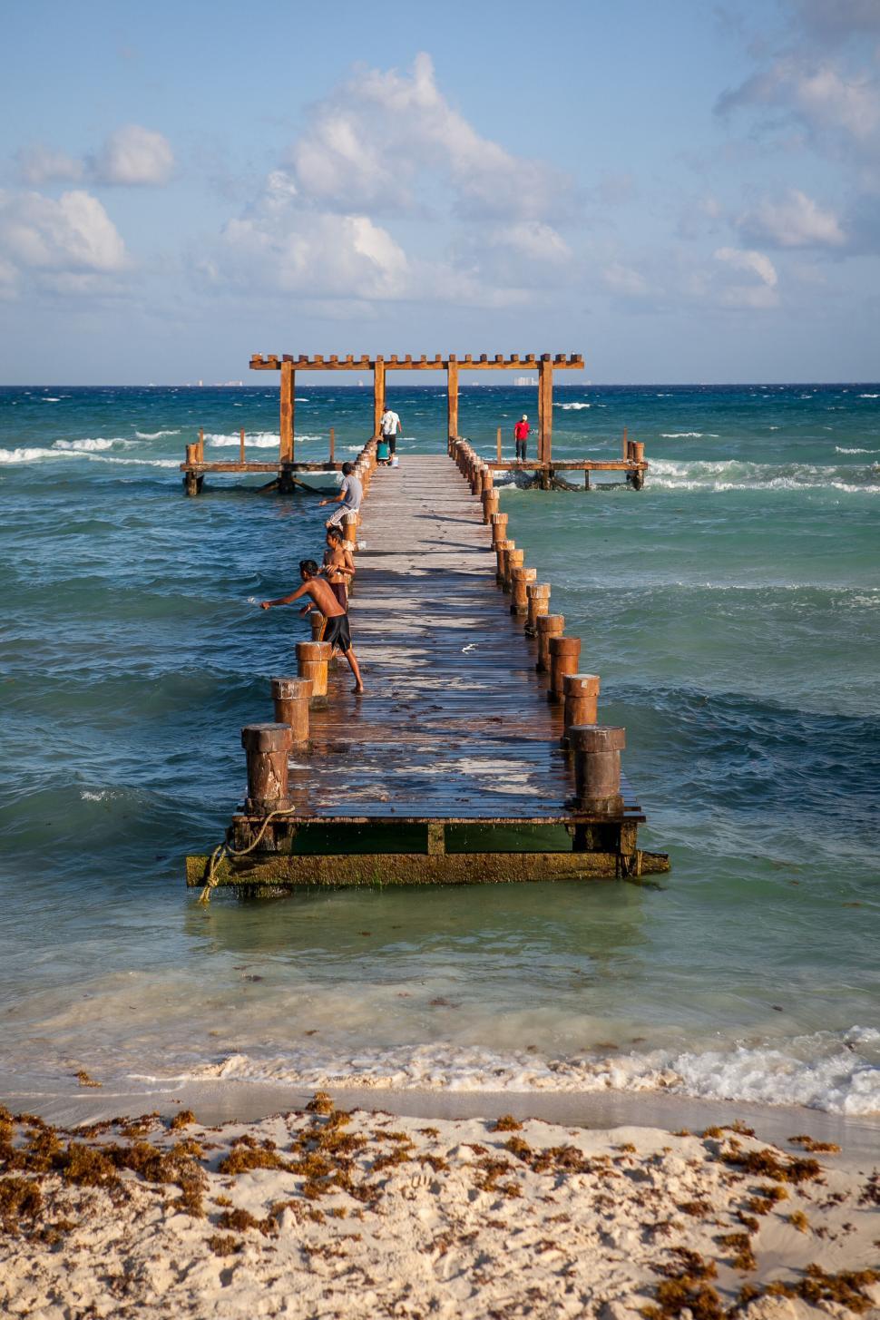Free Image of Wooden pier extending into turquoise ocean with people 