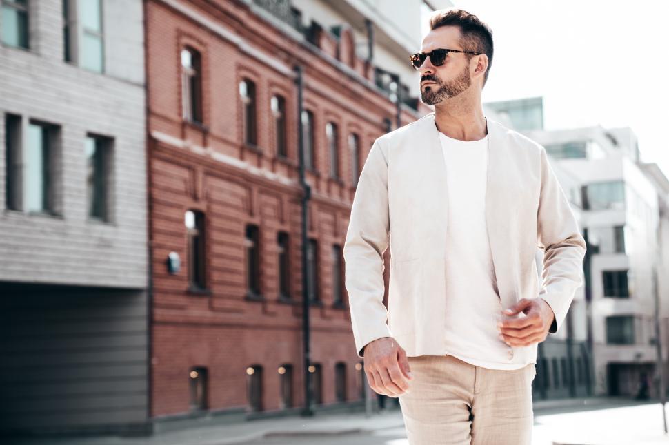 Free Image of Stylish man walking through urban area, showcasing modern fashion in bright daylight 