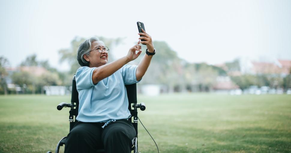 Free Image of Mature Asian woman on wheelchair use smartphone make video call 