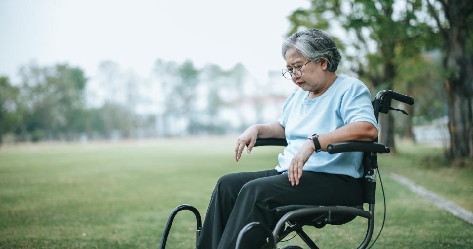 Free Image of Mature woman in wheelchair having knee pain with pain expression on face 