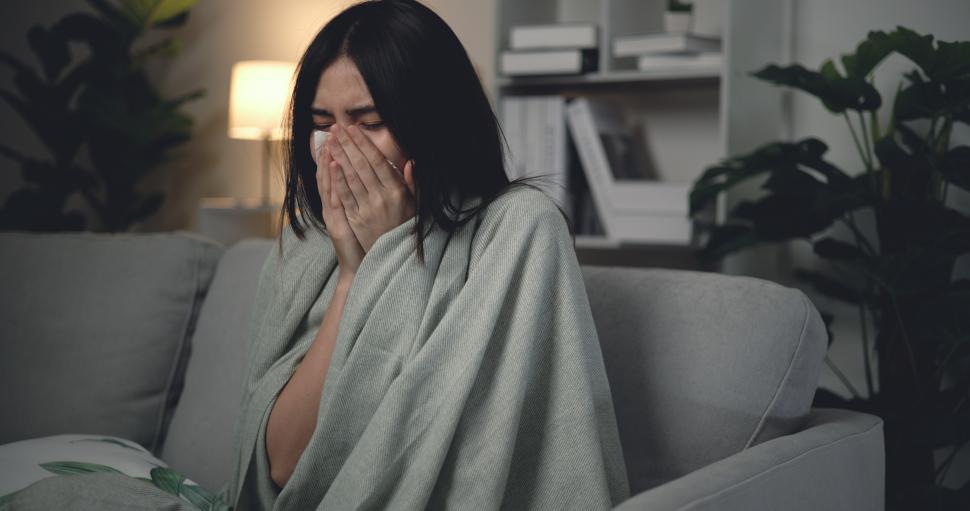 Free Image of Asian Young woman sitting under blanket with sneezing and flu at home 