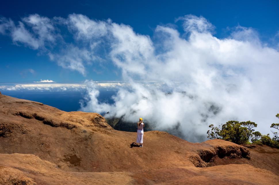 Free Image of Person standing on rocky cliff overlooking ocean view. 