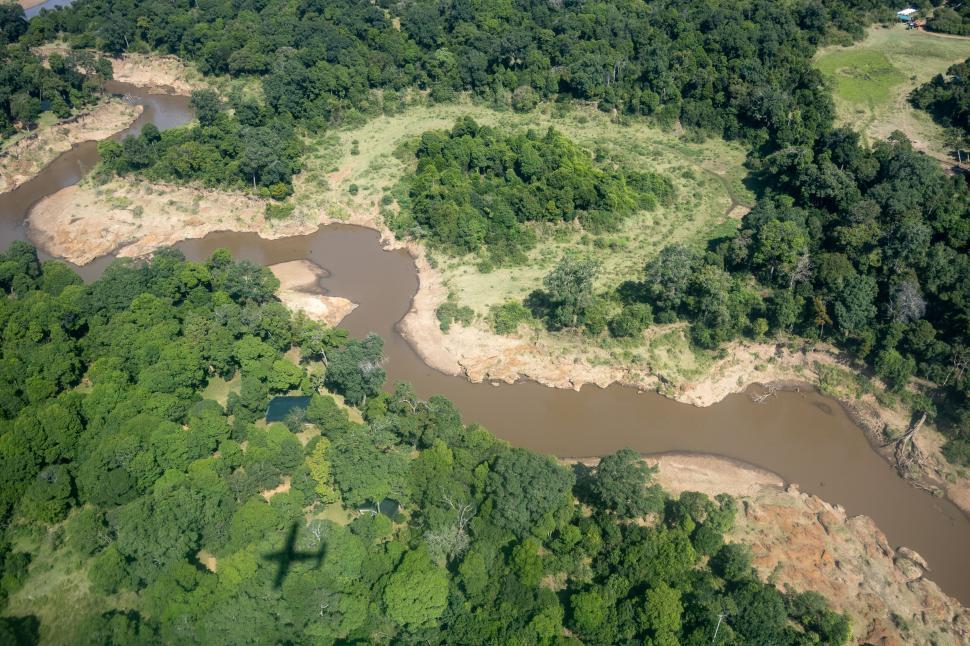 Free Image of Aerial view of a winding river through dense forest 