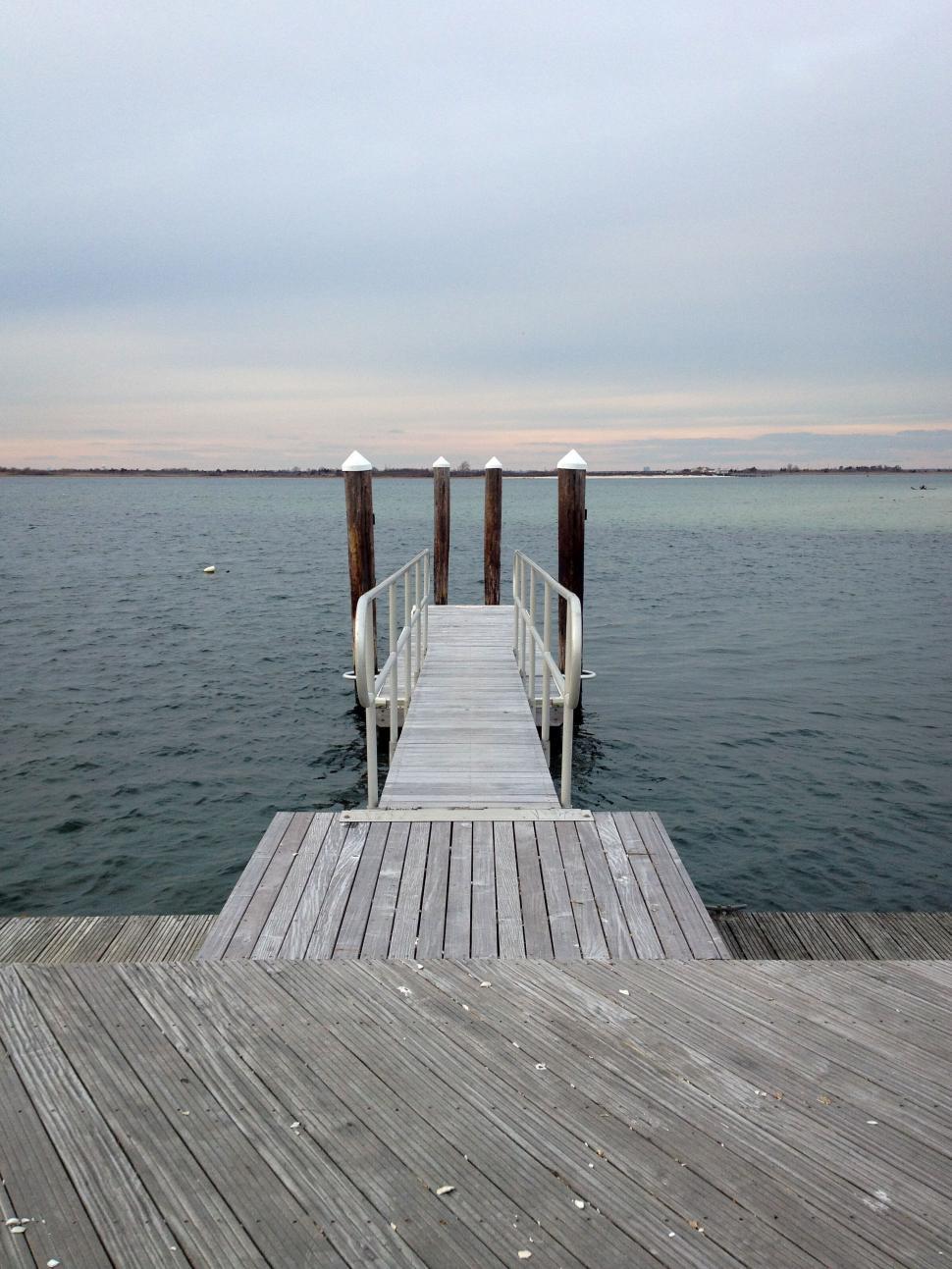 Free Image of Empty dock stretching into calm expansive water view 