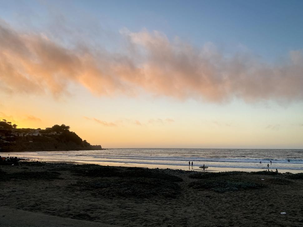Free Image of Beach sunset with waves crashing against the shore 