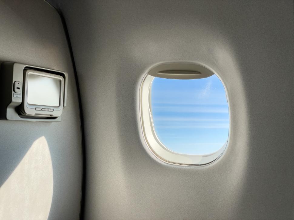 Free Image of Airplane window view with in-flight entertainment screen. 