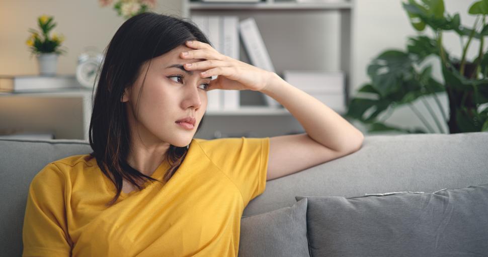 Free Image of Young asian woman sitting on sofa headache on sofa in living room 