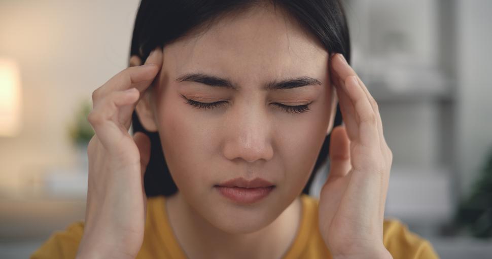 Free Image of Young asian woman sitting on sofa headache on sofa in living room 