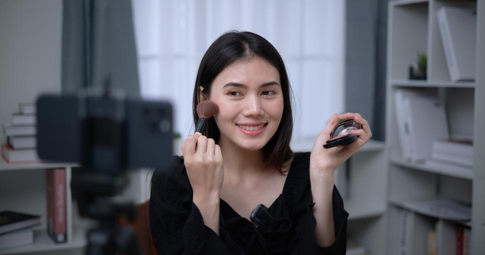 Free Image of Young Asian woman blogger shows how to make up cosmetics at home 