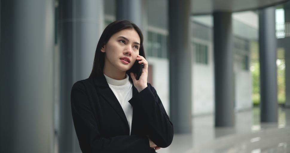 Free Image of Young Asian businesswoman in suit talking on  smartphone at modern office 