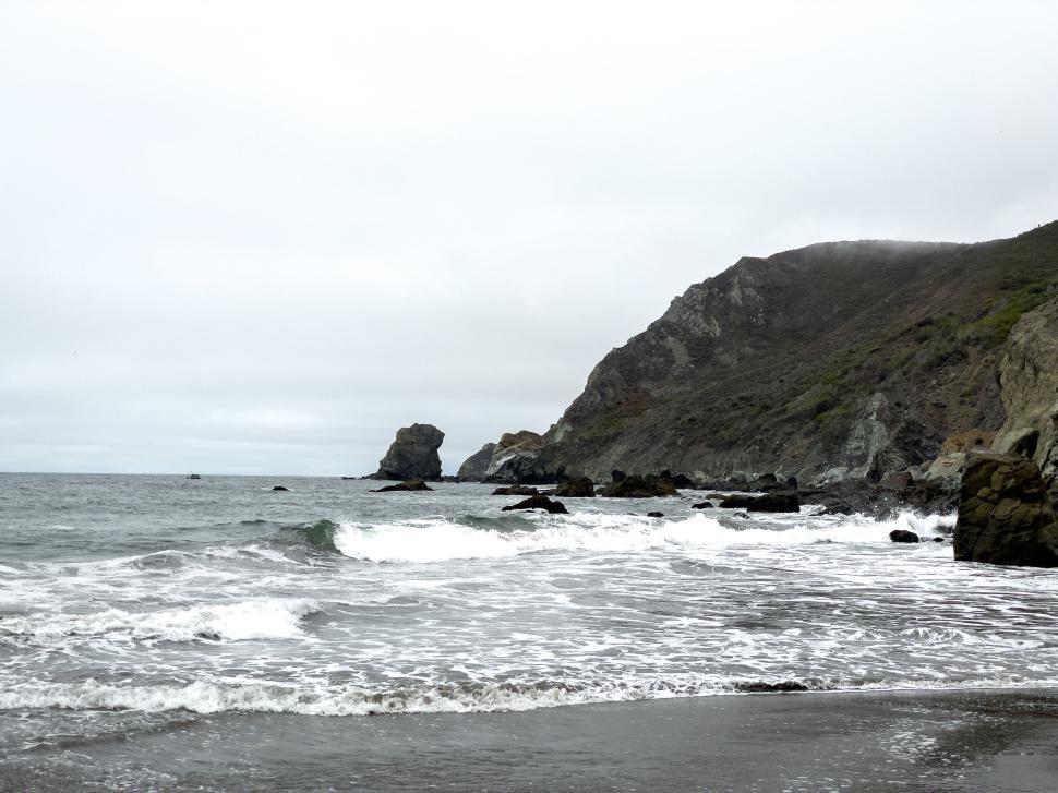 Free Image of Rocky coastline scenic view with waves crashing on shore. 
