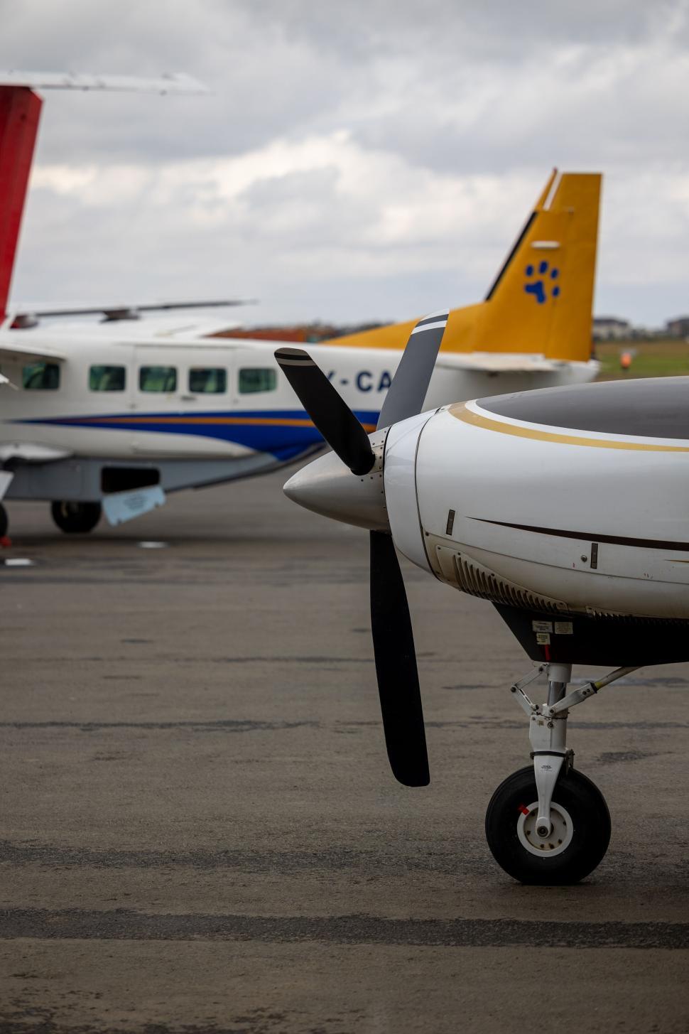 Free Image of Two small airplanes on tarmac with propeller in front 