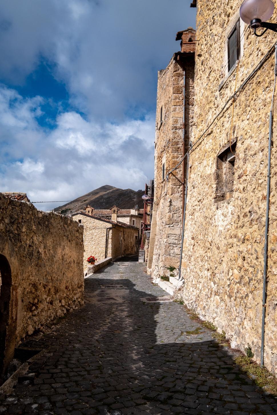 Free Image of Narrow cobblestone street with ancient stone buildings 