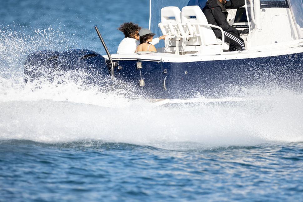 Free Image of Speedboat cutting through blue ocean waters, people onboard 