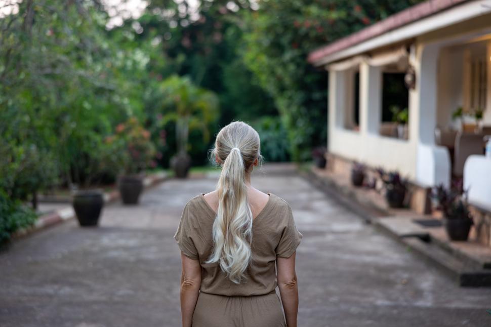 Free Image of Woman with long hair standing on path near cozy house 