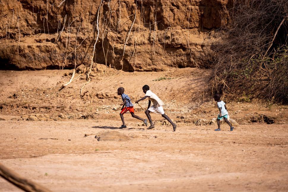 Free Image of Kids running joyfully across a dry, rocky terrain. 