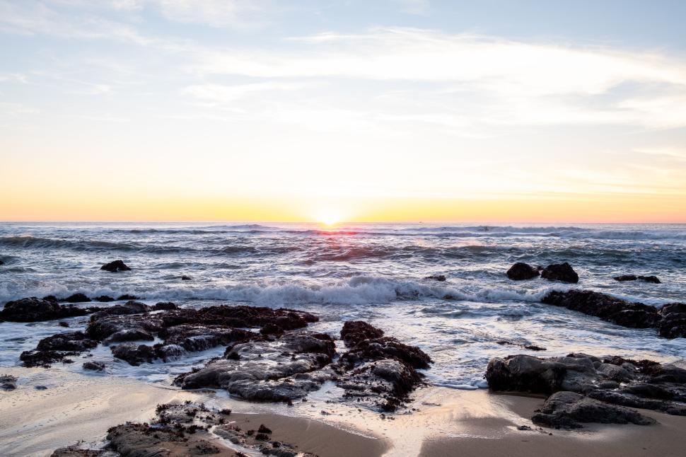 Free Image of Beautiful ocean waves crashing on rocky shore at sunset. 