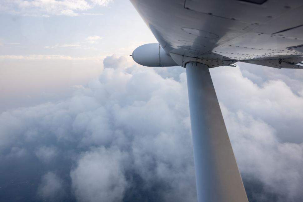 Free Image of Airplane wing cutting through fluffy white clouds mid-flight. 