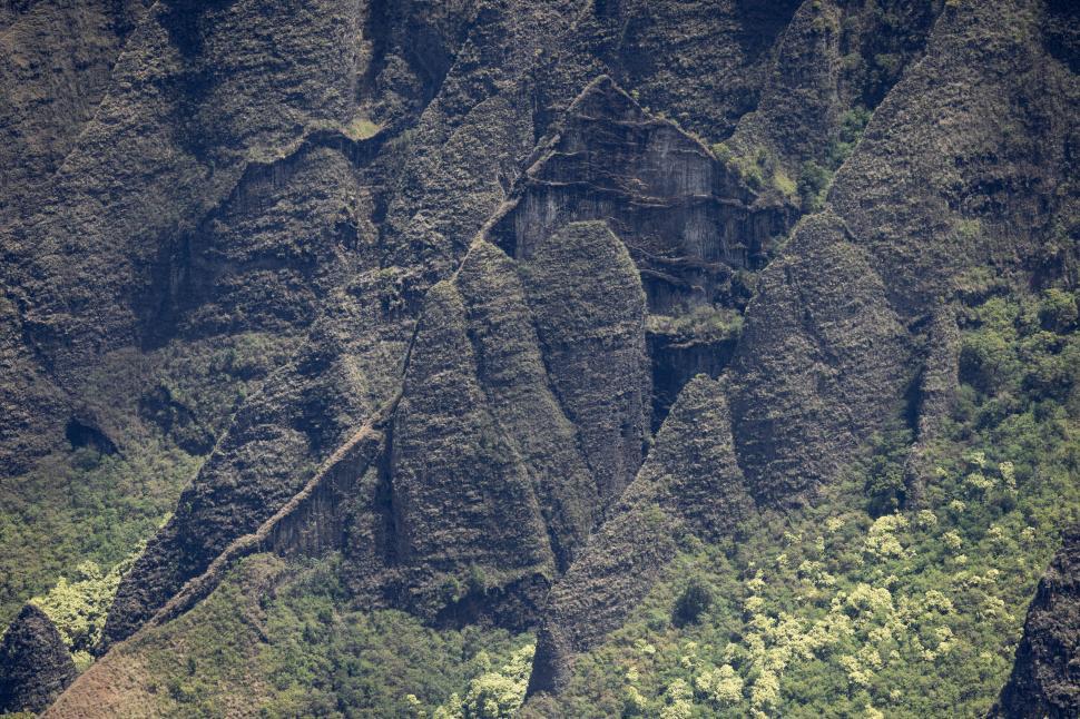 Free Image of Rugged mountain terrain, rocky cliffs amidst greenery. 