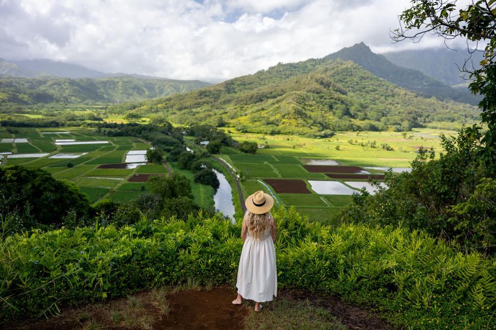 Free Image of Person in a hat enjoying a lush valley with green fields 