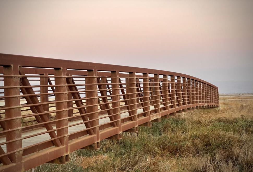Free Image of Rusty metal bridge spanning across a dry grass landscape 