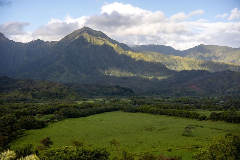 Free Image of Wide green field surrounded by tall mountainous terrain 