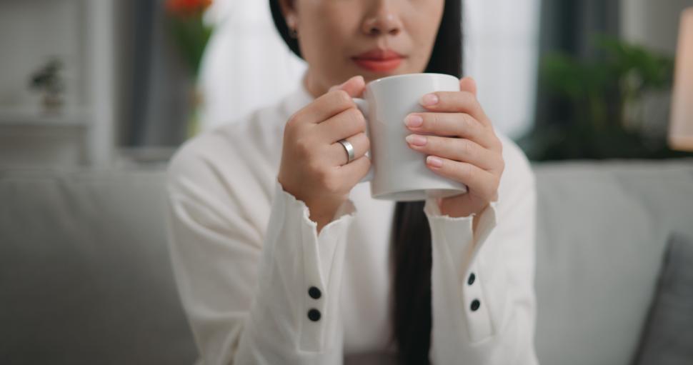 Free Image of Asian woman drinking a coffee while sitting on the sofa 