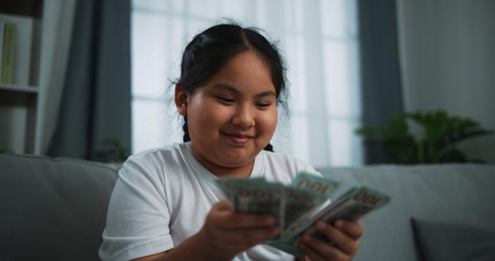 Free Image of Portrait of young Asian woman enjoy counting cash dollars banknotes on sofa in the living room at home. 
